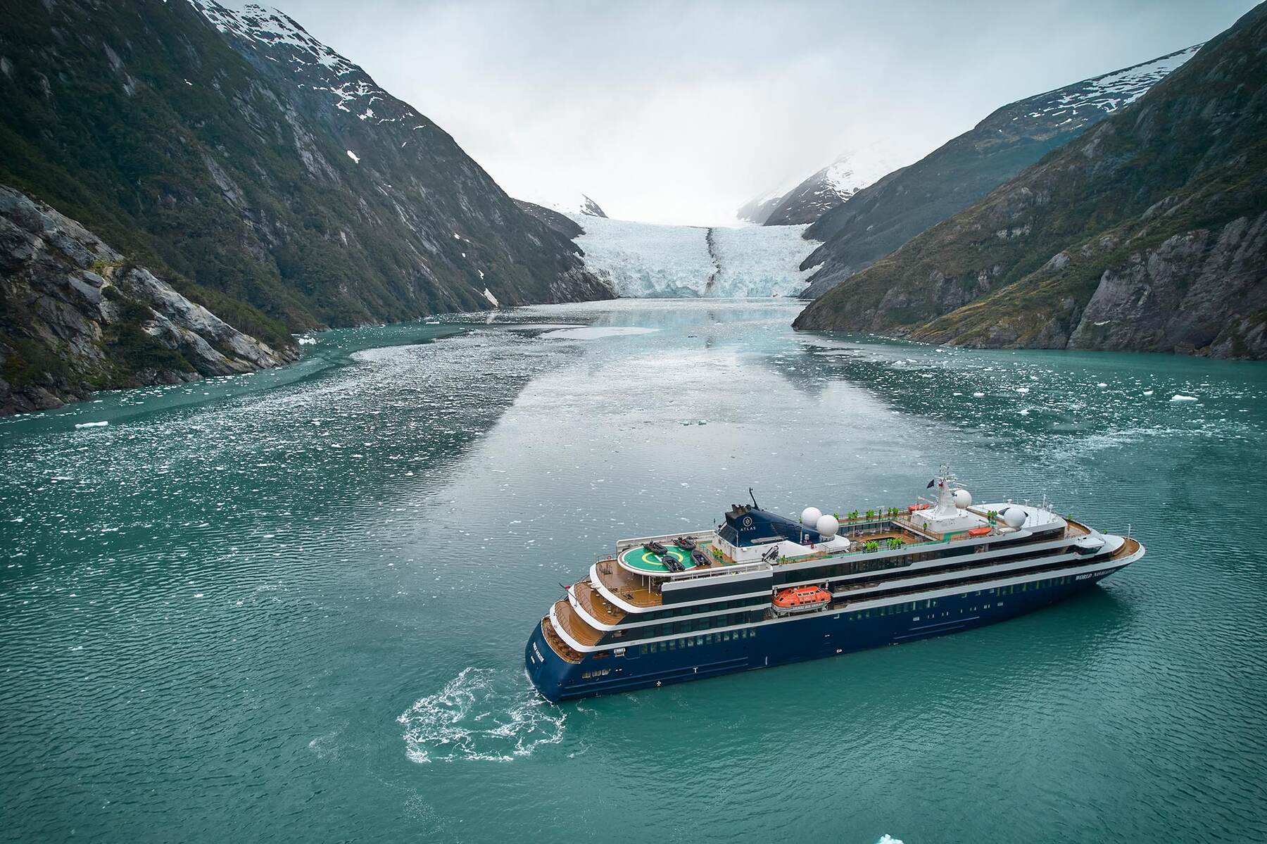 World Navigator, an Atlas expedition yacht, in a glacier fjord among drifting brash ice below snow-streaked peaks