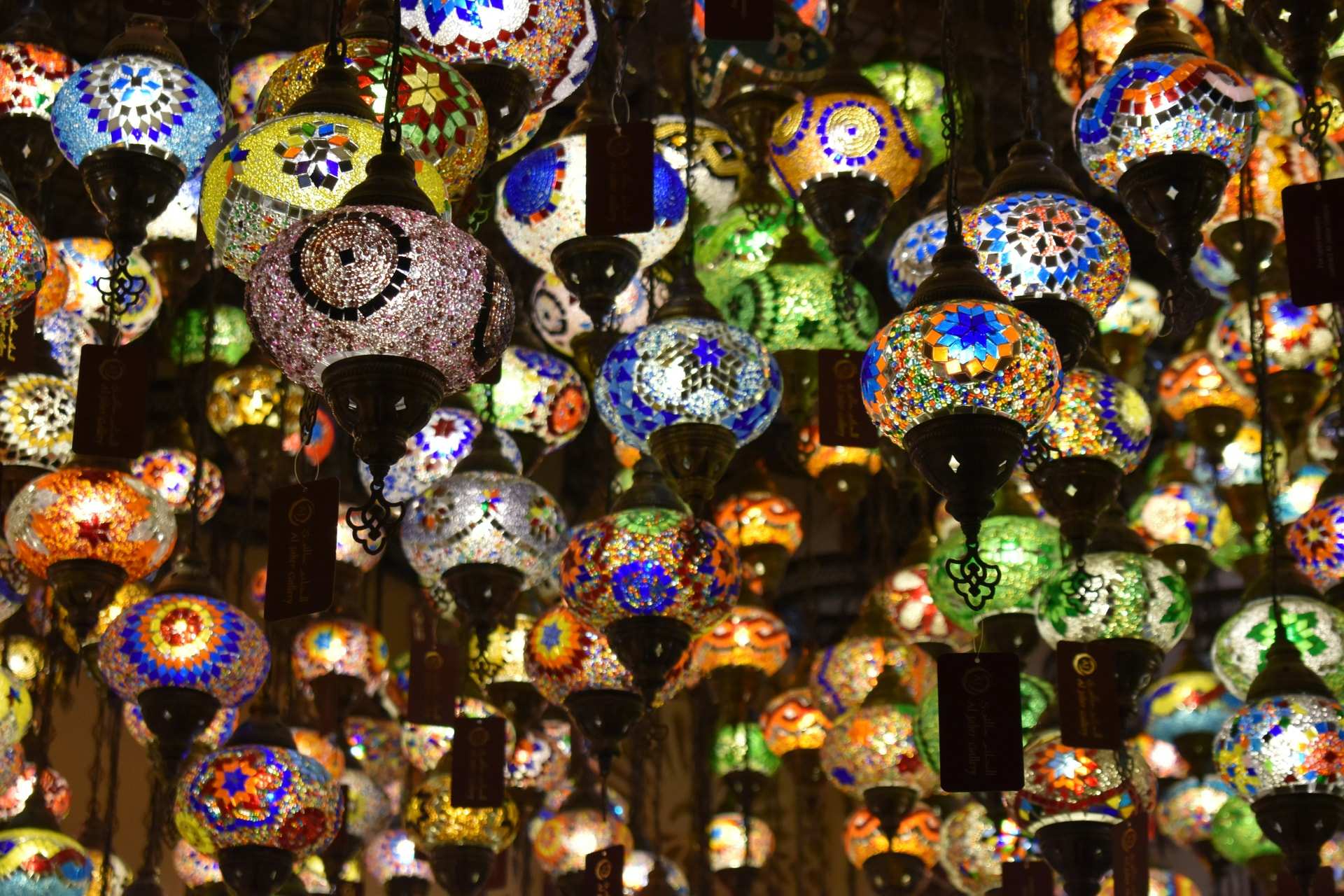 Hundreds of lit mosaic glass lamps in many colours hang from the ceiling of a shop in Souk Madinat Jumeirah