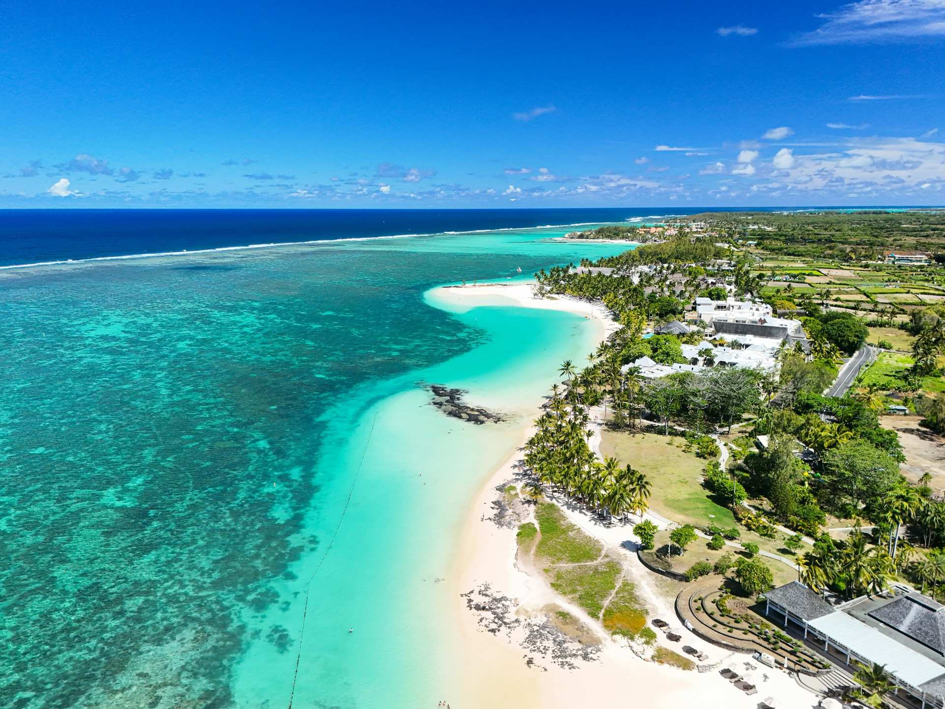 Aerial view of a long white beach and a pale turquoise lagoon inside the reef at Belle Mare, on the east coast of Mauritius