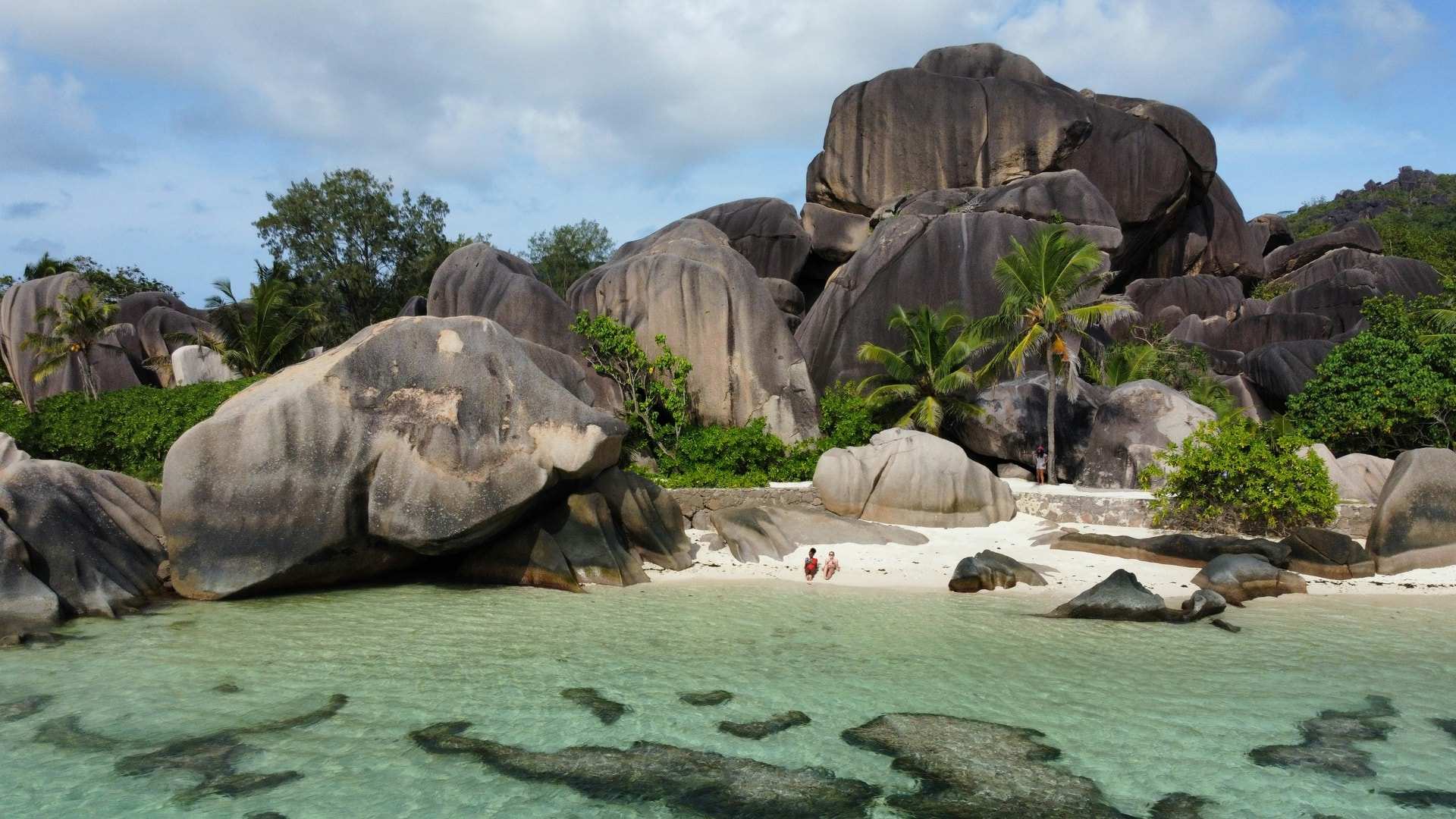 Huge rounded granite boulders and palms above a shallow, clear lagoon at Anse Source d'Argent on La Digue