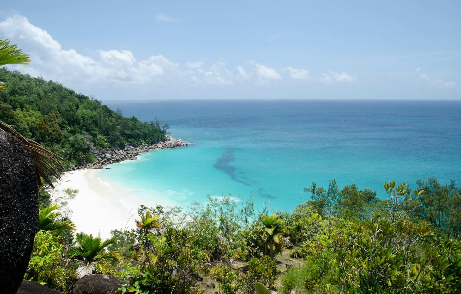 Looking down through green scrub to the white sand and turquoise water of Anse Georgette on Praslin, Seychelles