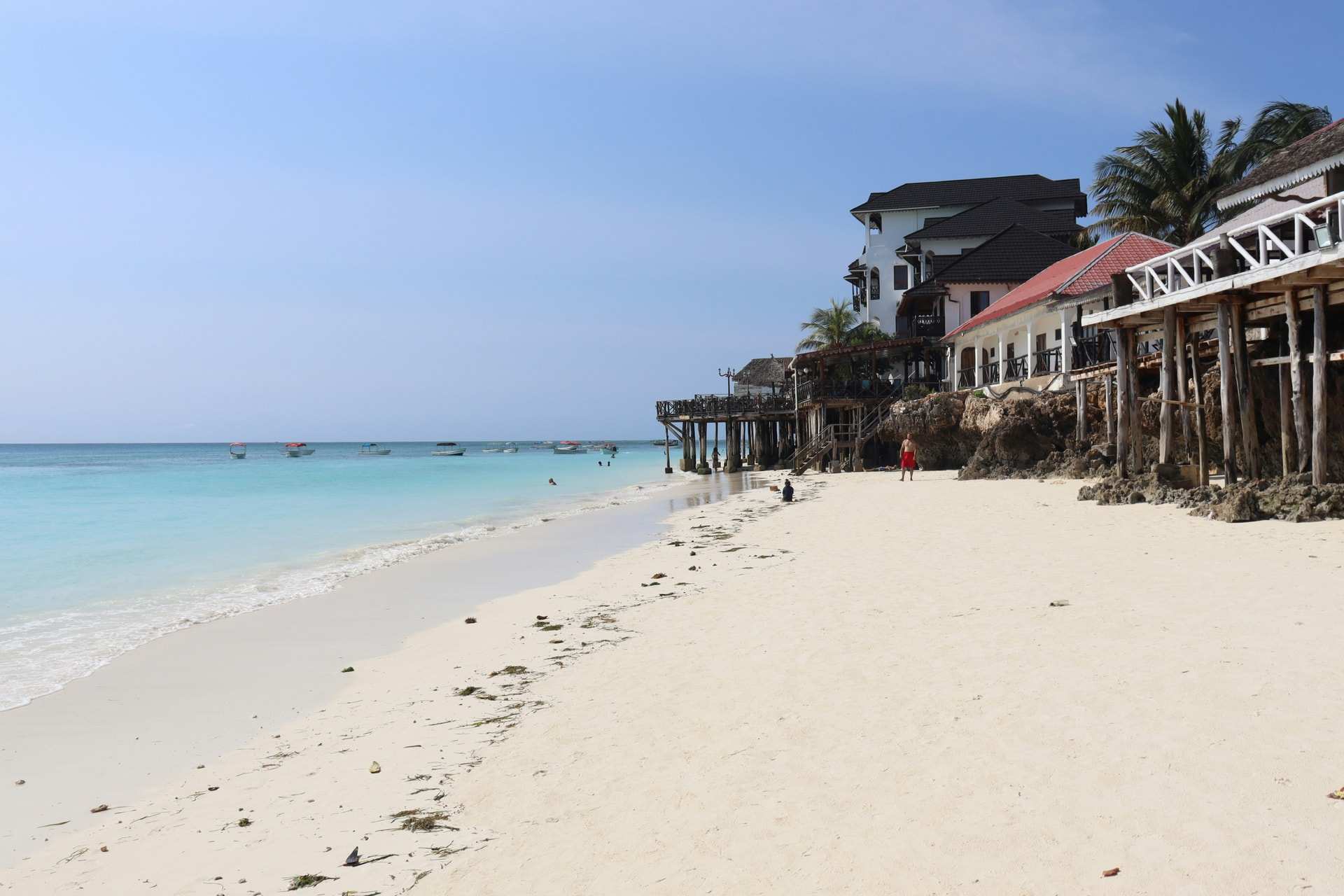 A white sand beach curving past hotels and palms at Nungwi, on the northern tip of Zanzibar, with calm turquoise water