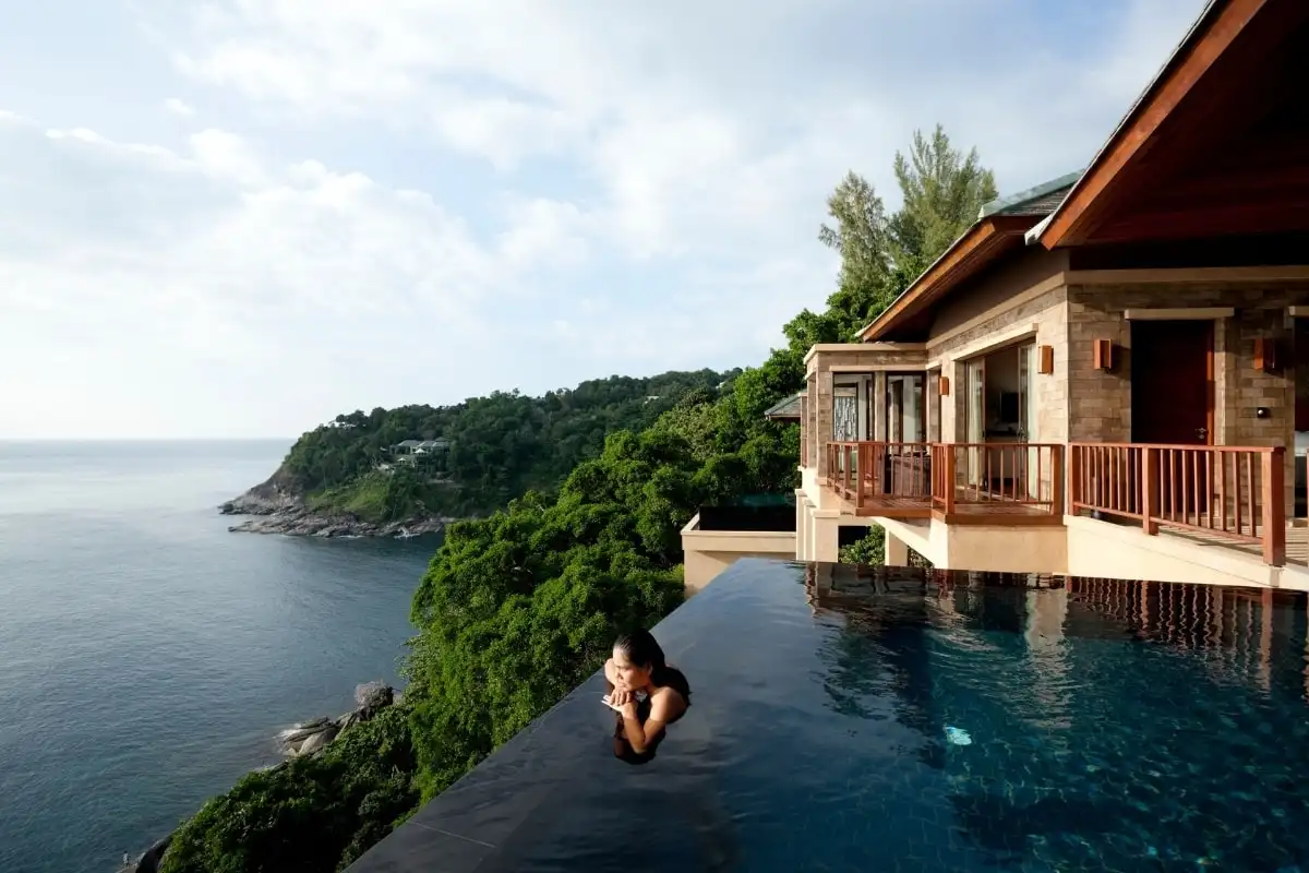 A woman in an infinity pool at a clifftop villa above the sea