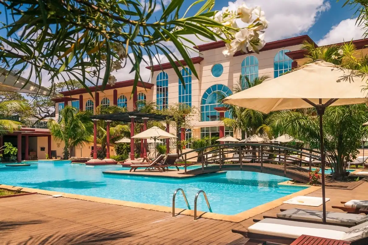 A hotel pool with parasols and a footbridge