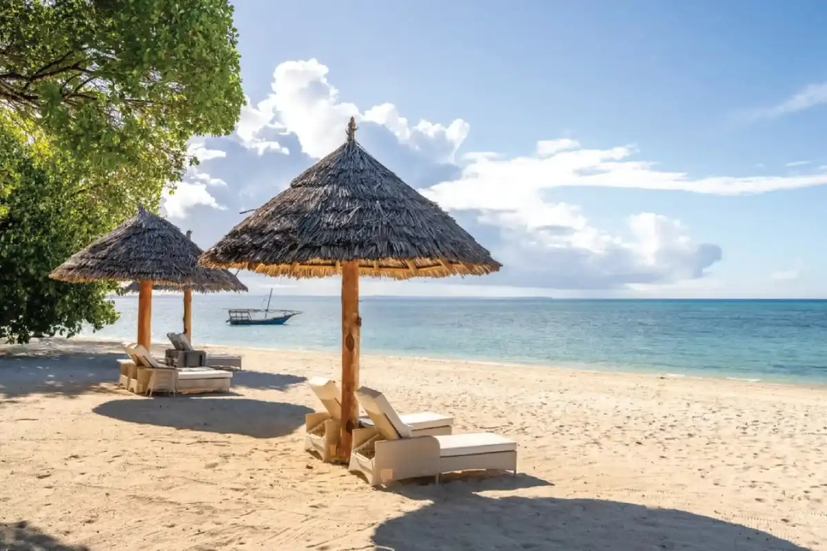 A thatched parasol and loungers on the sand