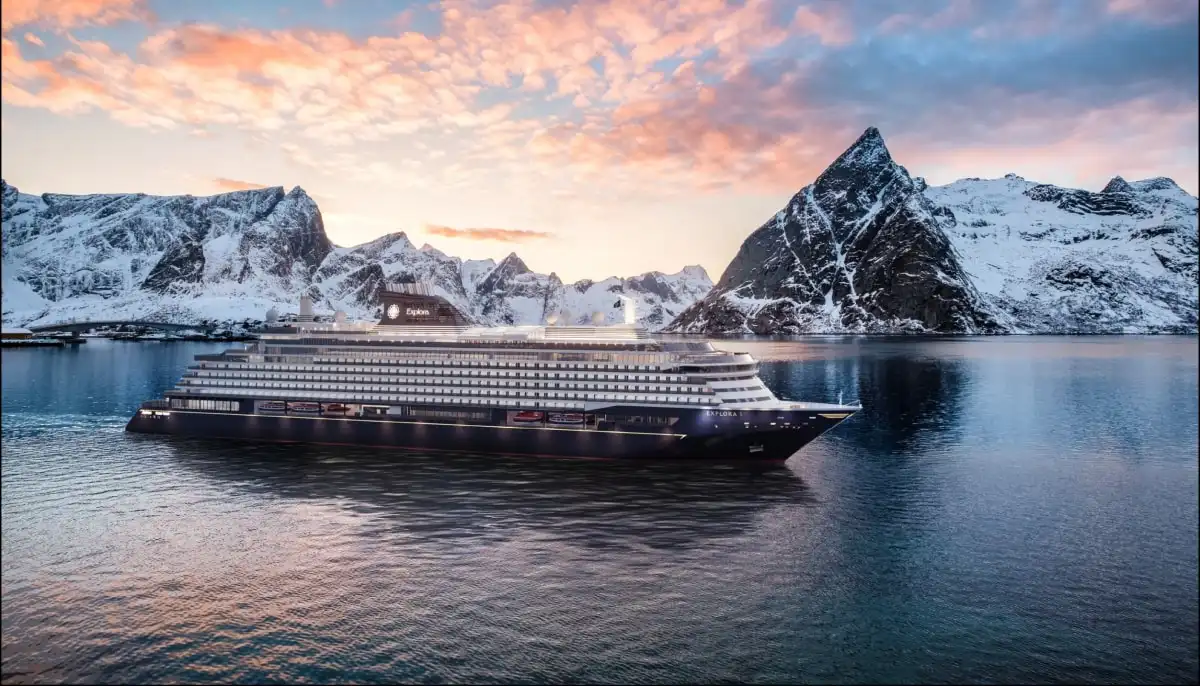 A cruise ship in a fjord below snow-covered peaks