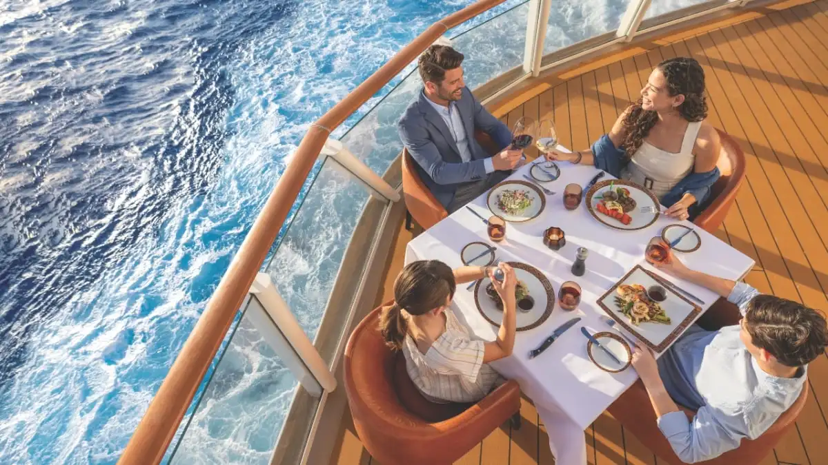 A couple dining at a table on a balcony above the sea