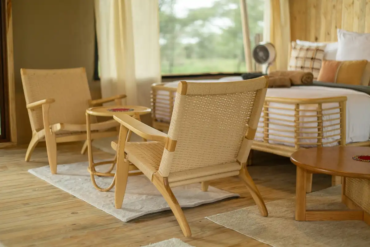 A tented suite’s sitting area in woven cane, open to green bush beyond