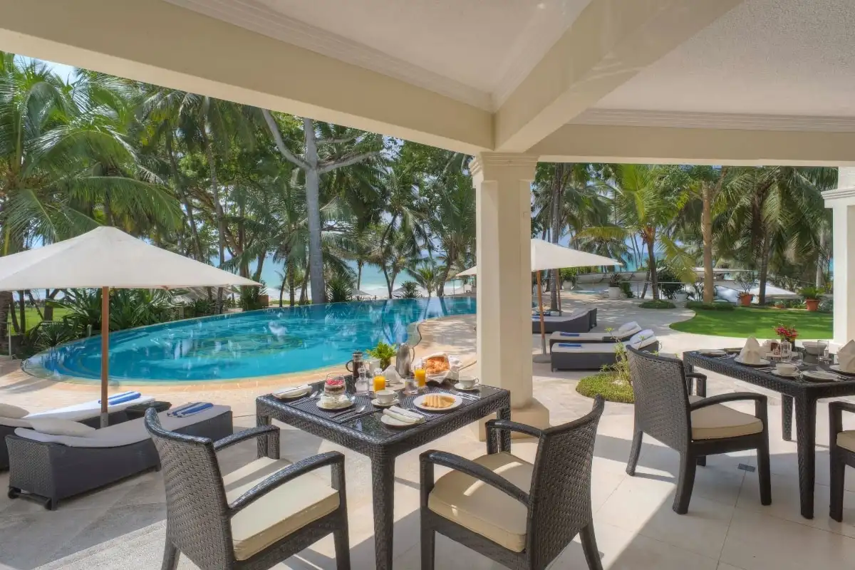 A covered terrace laid for a meal beside a pool