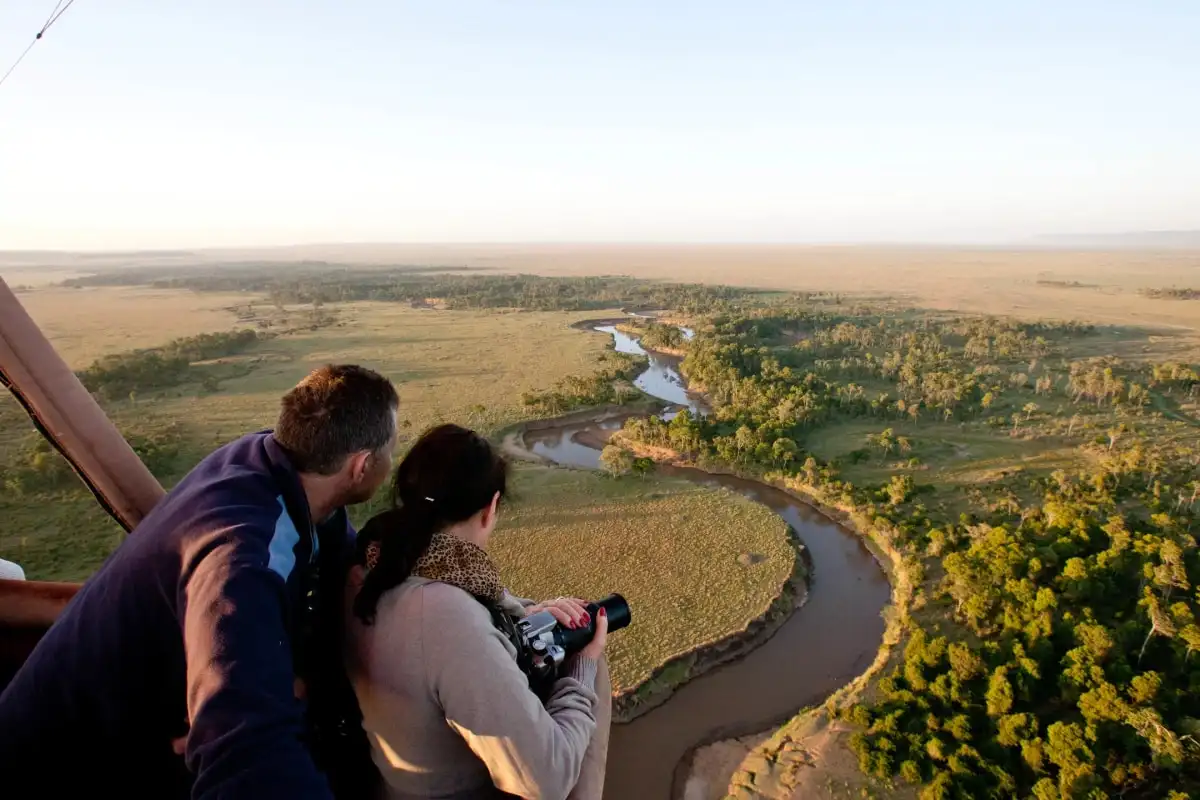 A couple looking out over a river bend from a balloon basket