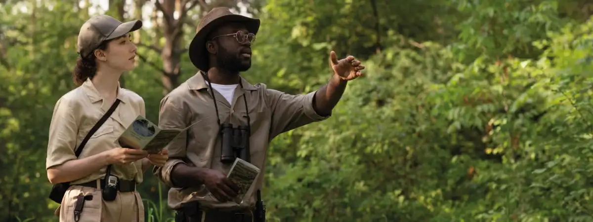 A safari guide with binoculars pointing something out