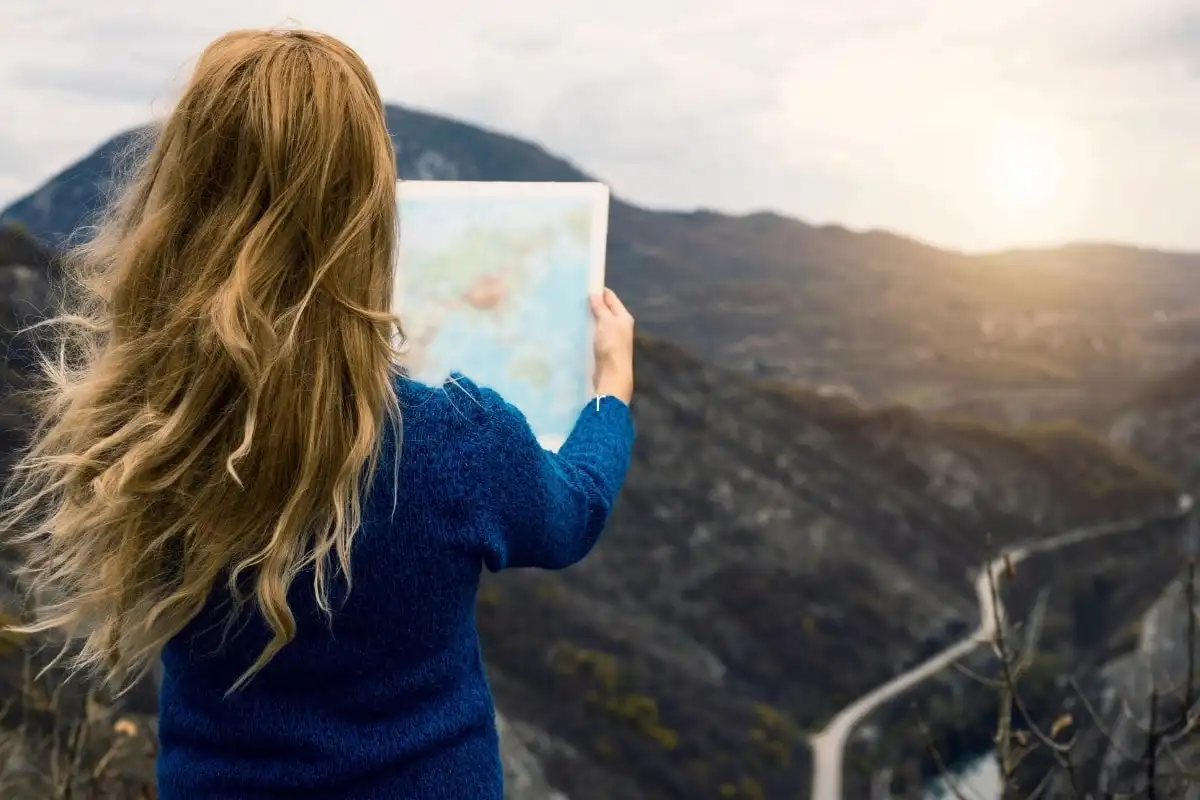 A traveller holding an open map with green hills ahead