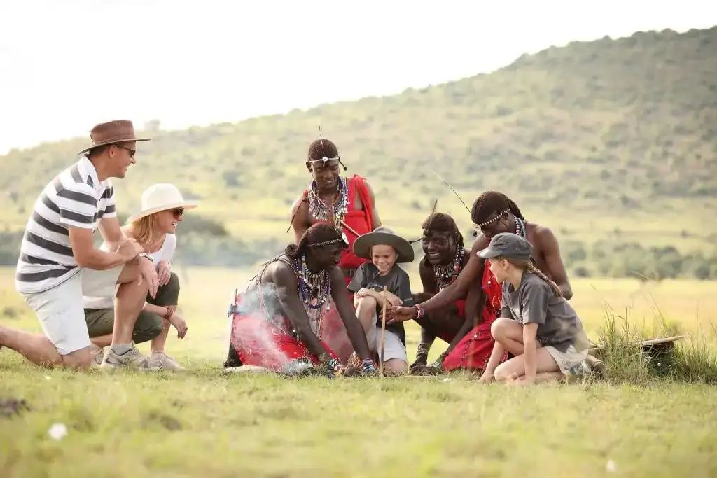 Visitors sitting with Maasai men as they light a fire