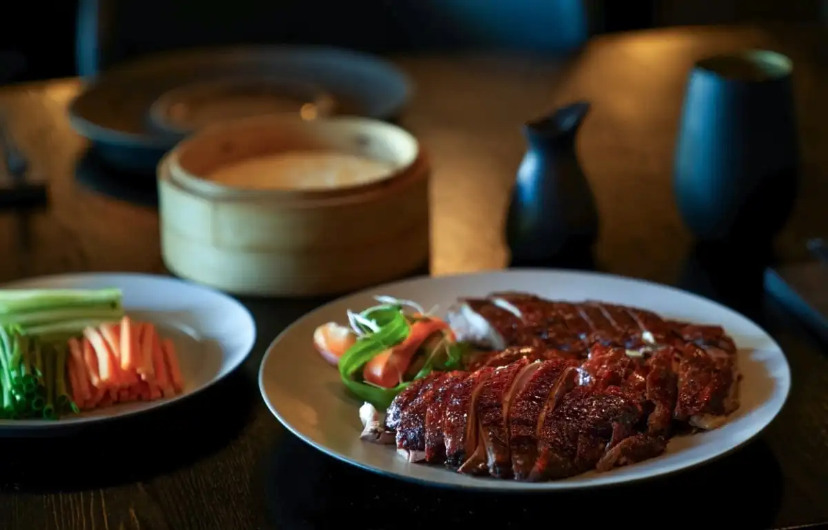 A plated dish served with a bamboo steamer alongside