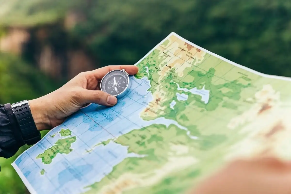 A hand holding a compass over a map