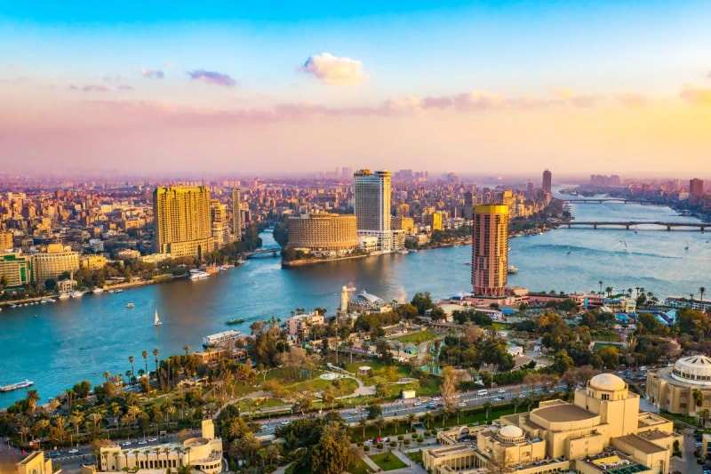 Cairo along the Nile at dusk, high-rises on the far bank and bridges crossing the river