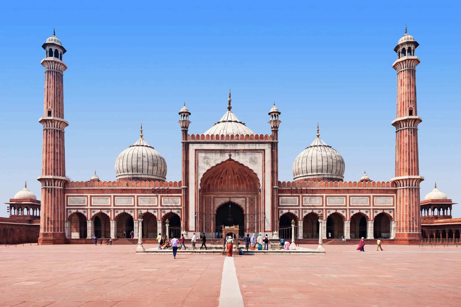 Jama Masjid in Delhi, the red sandstone prayer hall and its three marble domes between two tall minarets, seen across the courtyard