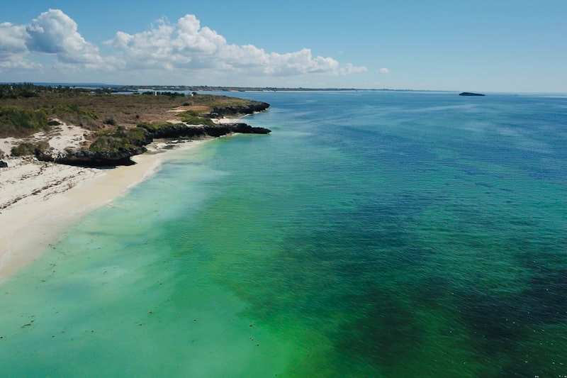 White sand and turquoise shallows along a coral-rock coastline seen from the air