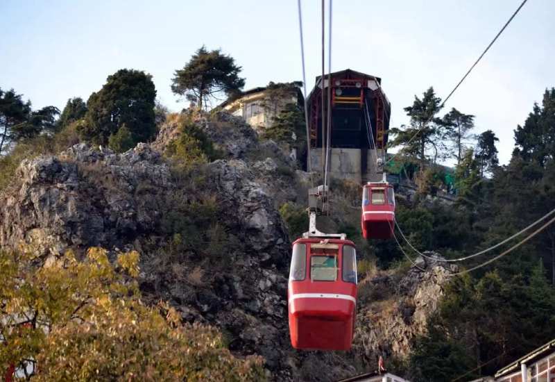 Red cable cars on the ropeway up to Gun Hill in Mussoorie, the top station on a rocky crag above