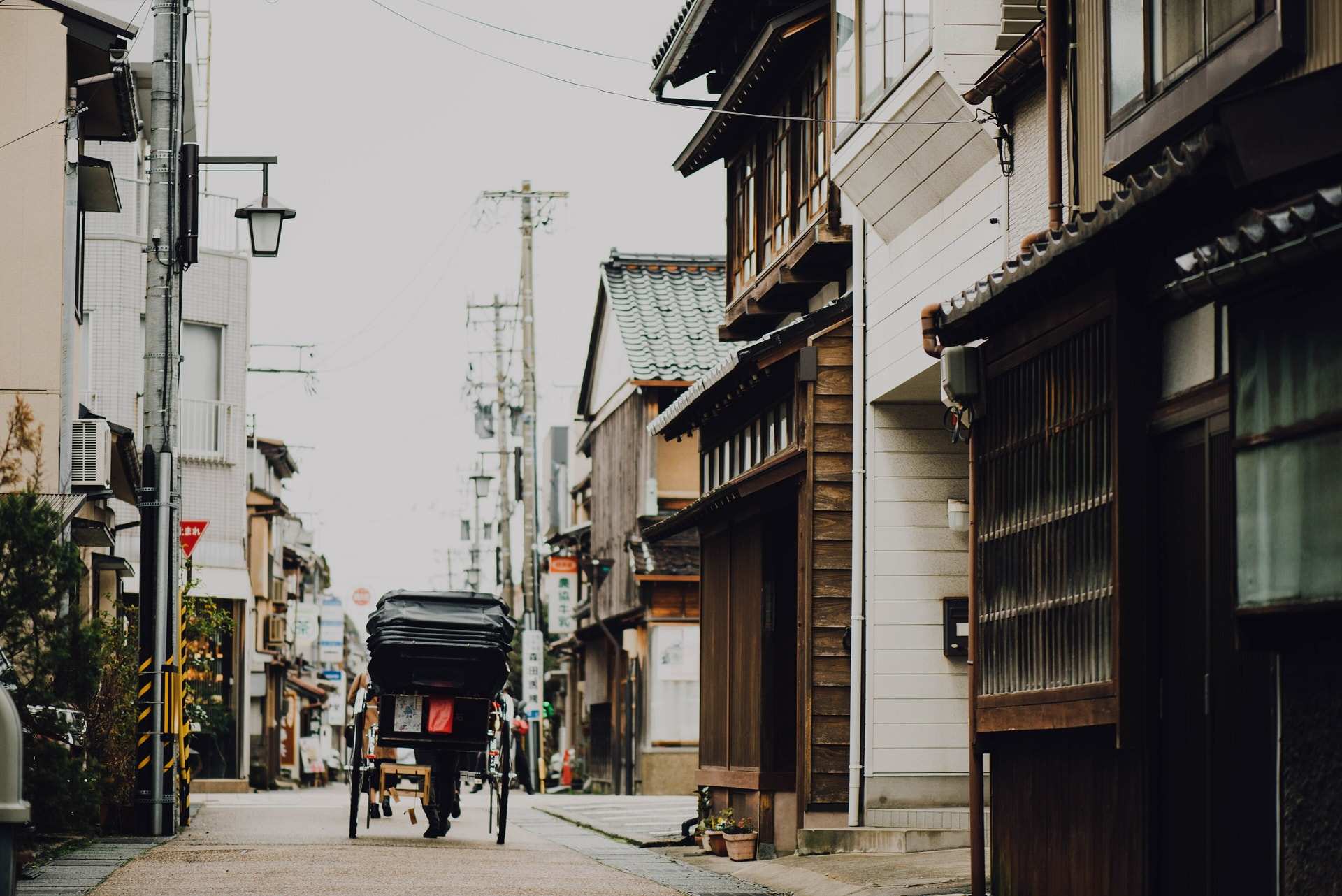 A rickshaw waiting in a quiet street of old wooden townhouses in Kanazawa's Higashiyama district