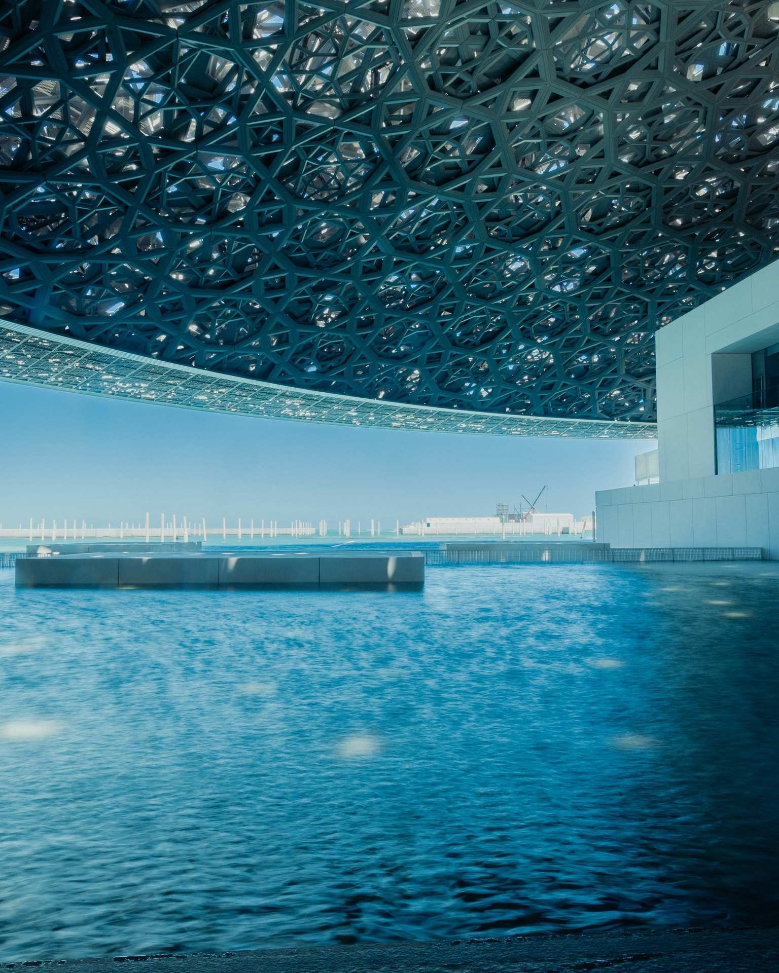 The Louvre Abu Dhabi's latticed dome over still water, in a long exposure