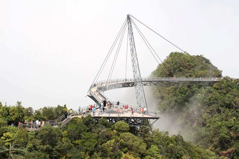 The curved Langkawi Sky Bridge hung from a single pylon above the rainforest, visitors along its deck