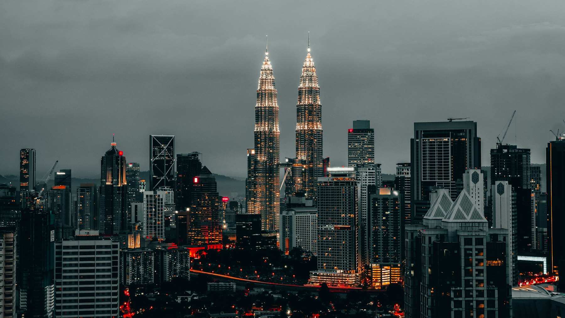 The Petronas Twin Towers lit above the Kuala Lumpur skyline at dusk