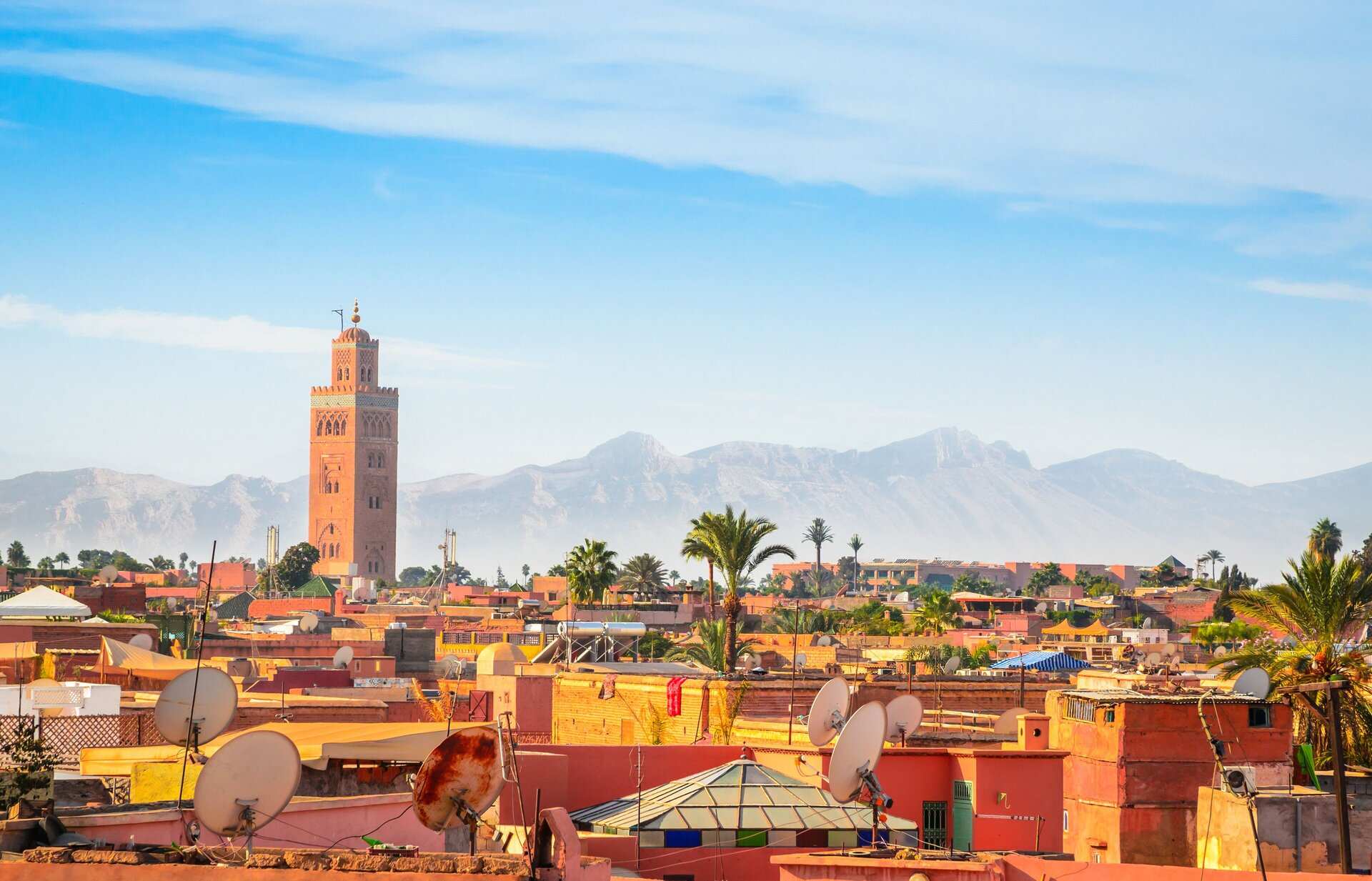 The Koutoubia minaret above the rooftops of the Marrakech medina, with the High Atlas mountains behind