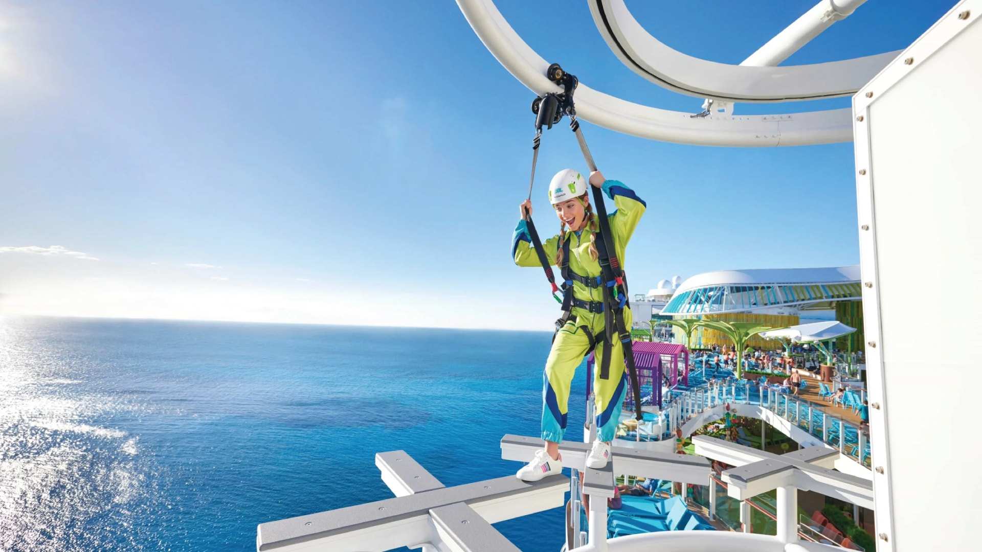 A guest riding a zip line high above the upper deck, ocean beyond