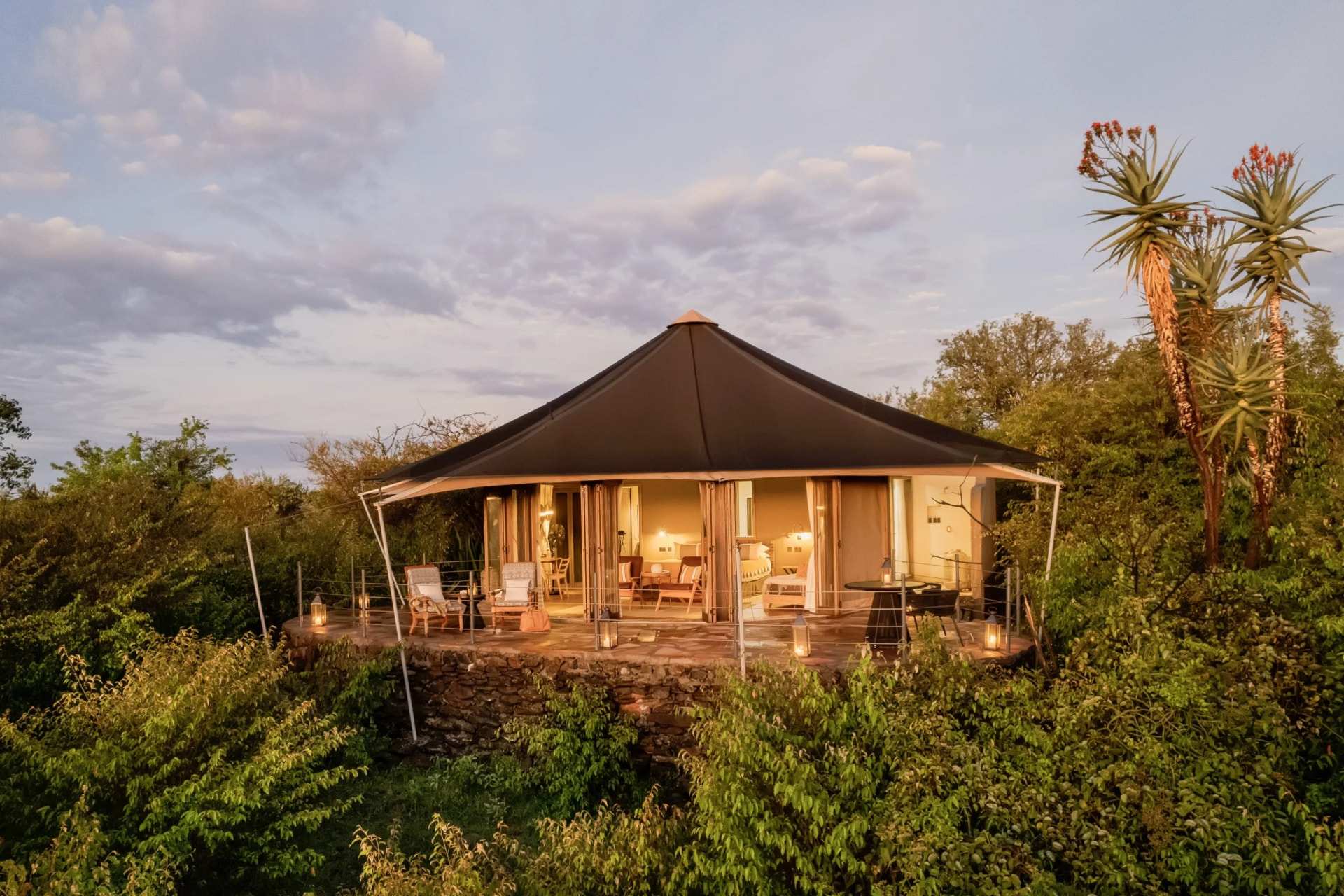 A tented suite lit up at dusk in the bush