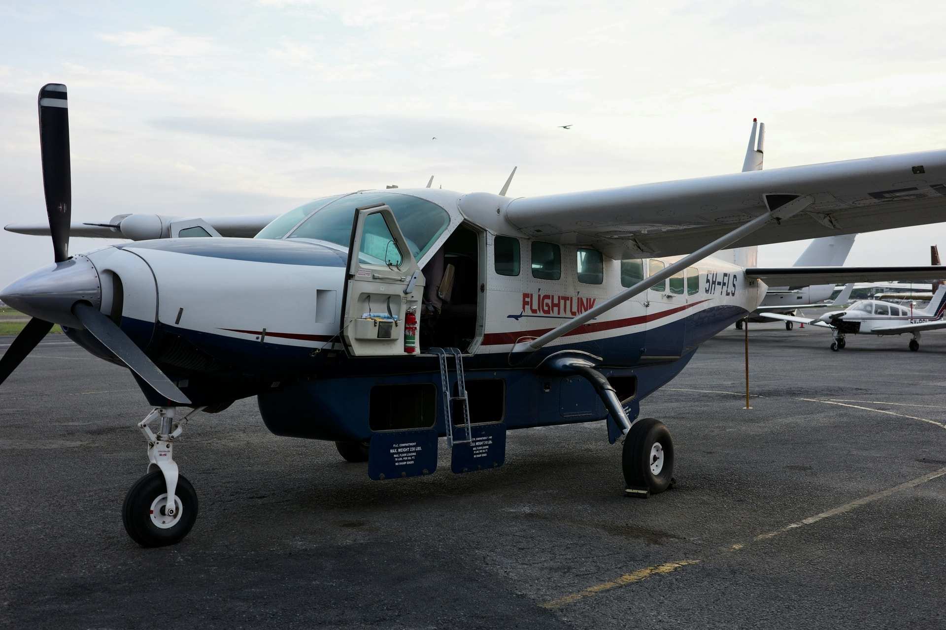 A single-engine Cessna Caravan parked on the apron at Wilson Airport, Nairobi, its passenger door and steps open