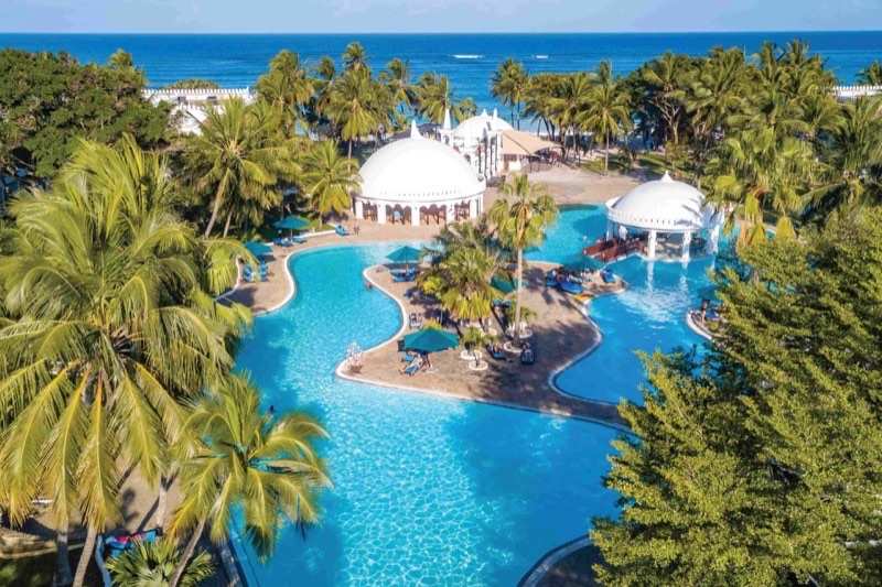 White sand and turquoise surf on the Diani shoreline, palms along the headland
