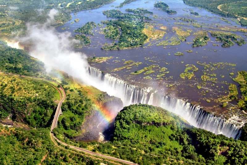 Victoria Falls from the air, the island-dotted Zambezi pouring into the gorge, spray and a rainbow rising