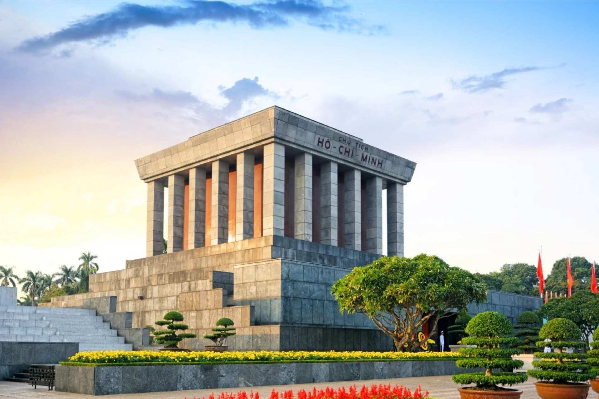 The Ho Chi Minh Mausoleum in Hanoi, clipped shrubs and red flowers in front