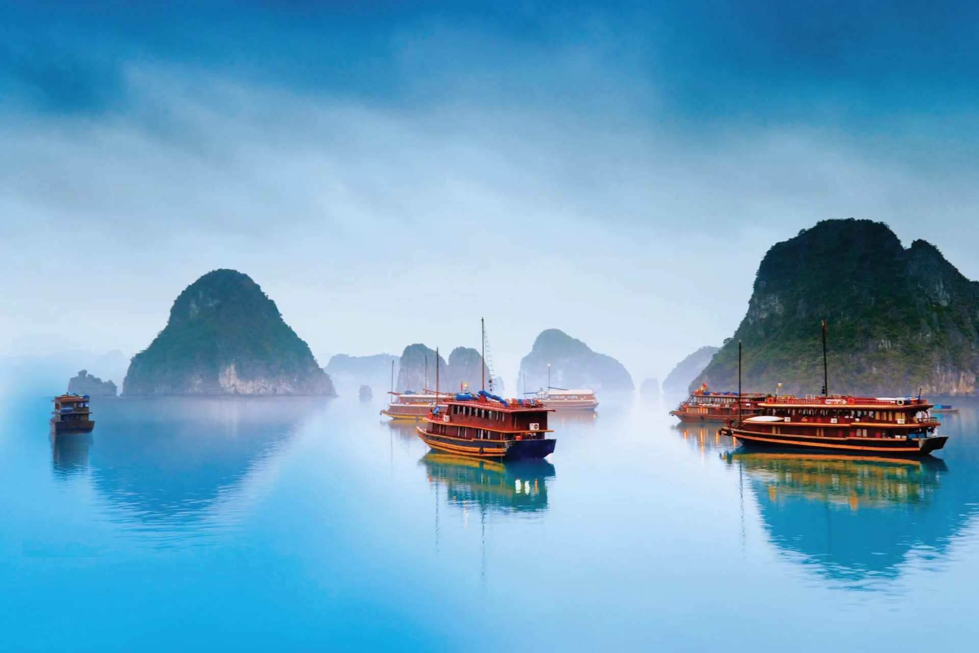 Limestone islands and still water in Ha Long Bay at first light